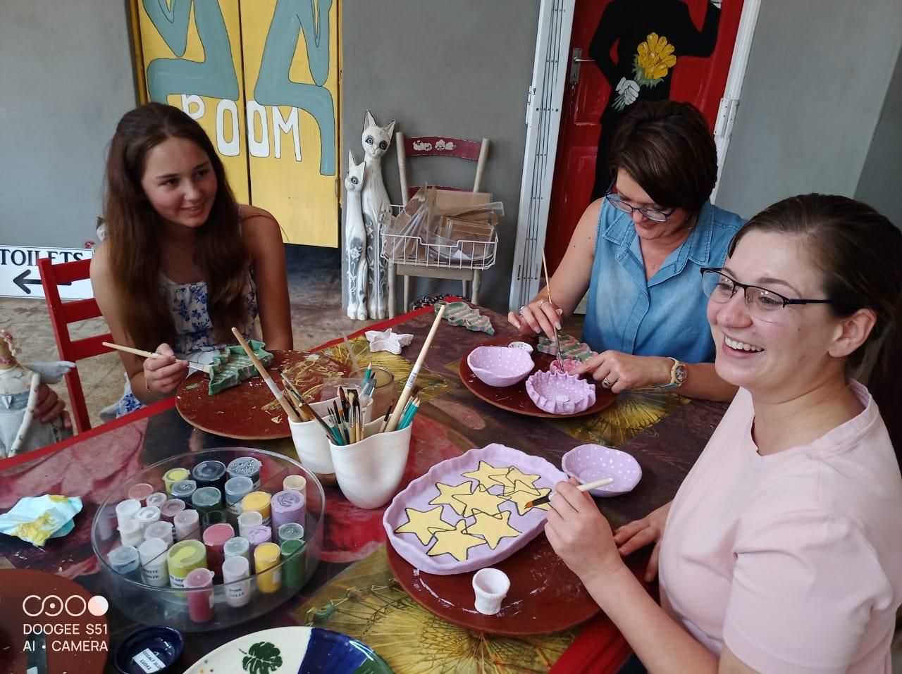 Three friends painting star and polka-dot designs on bowls