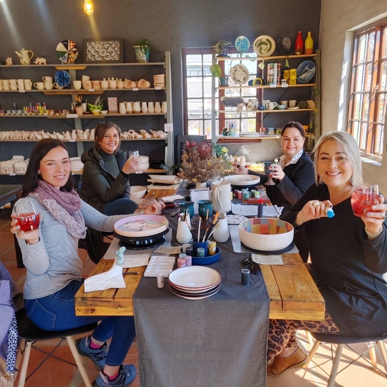 Friends raising a toast while painting bowls and plates at Ponieskrantz