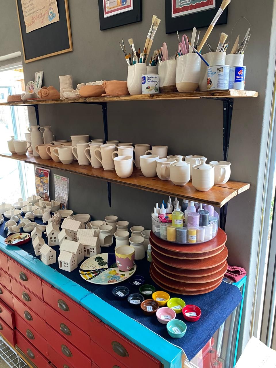 Shelves of unpainted bisque mugs, jugs and houses ready to paint